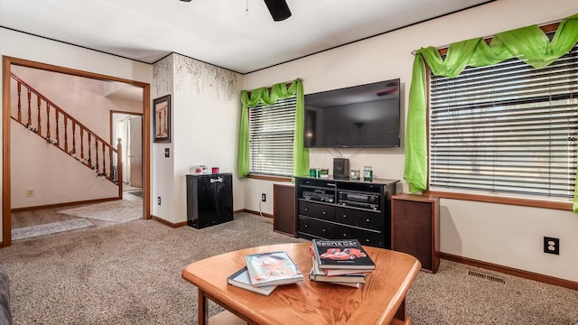 carpeted living area featuring visible vents, baseboards, ceiling fan, and stairs