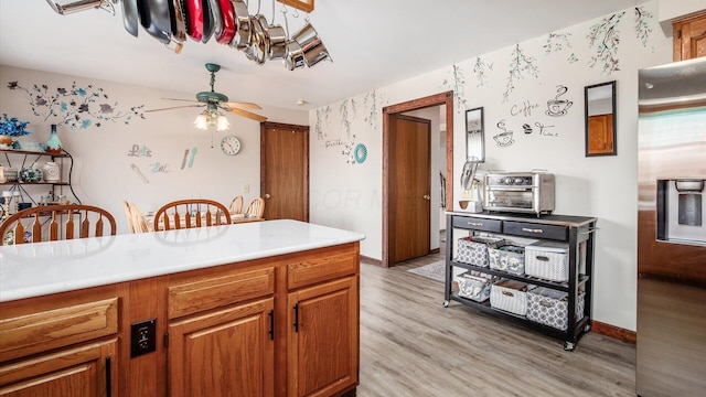 kitchen featuring light countertops, a ceiling fan, light wood-style floors, and brown cabinets