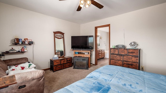 carpeted bedroom featuring baseboards, ensuite bath, and a ceiling fan