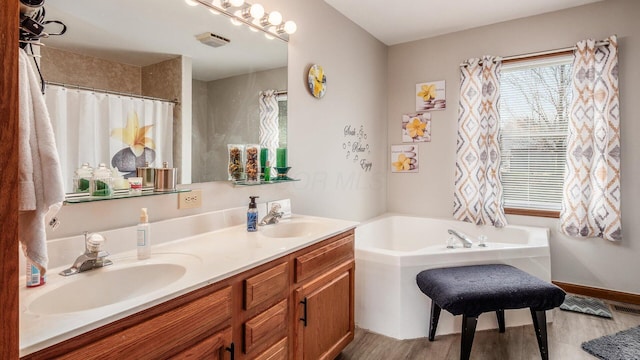 bathroom featuring a bath, double vanity, wood finished floors, and a sink