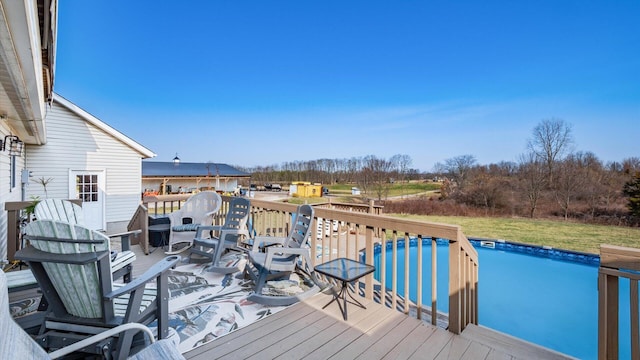 wooden terrace with an outdoor pool and a yard