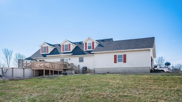 rear view of property featuring a yard, a deck, and roof with shingles