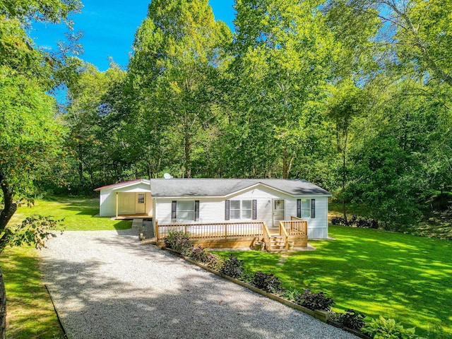 manufactured / mobile home with driveway, a front yard, and a wooden deck