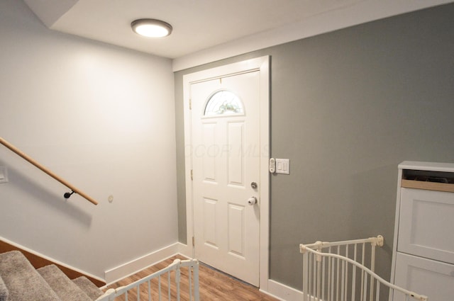 foyer featuring light wood-type flooring, baseboards, and stairs