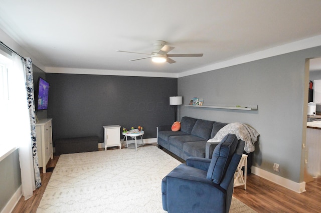 living area with a ceiling fan, baseboards, and wood finished floors