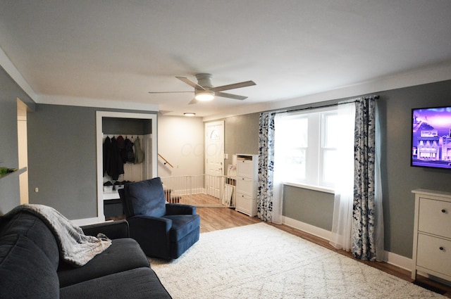 living area featuring a ceiling fan, baseboards, and wood finished floors