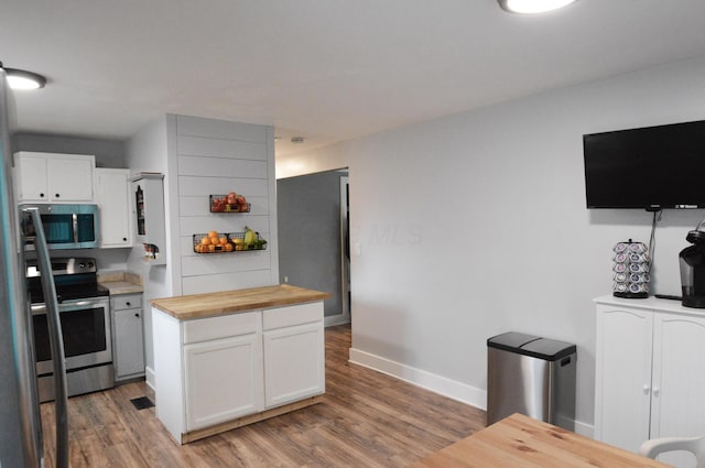 kitchen with stainless steel appliances, butcher block countertops, light wood-style floors, and white cabinets