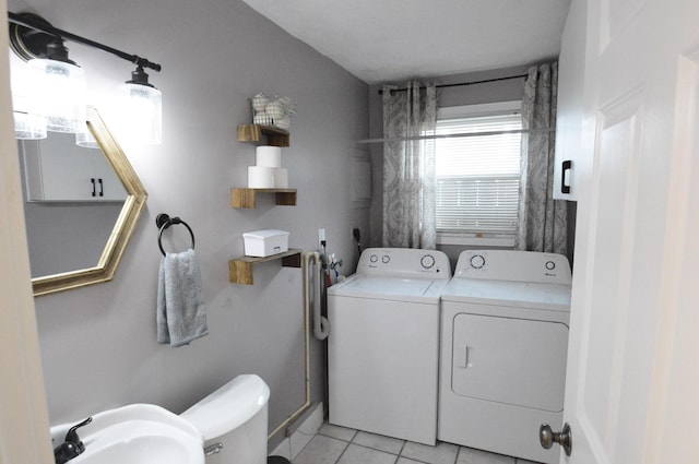 clothes washing area featuring light tile patterned floors, washing machine and dryer, laundry area, and a sink