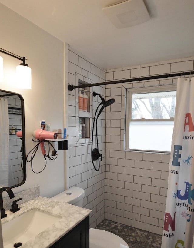 bathroom featuring tiled shower, vanity, and toilet