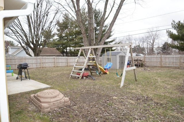 view of playground with a fenced backyard, a storage unit, a patio, and an outbuilding