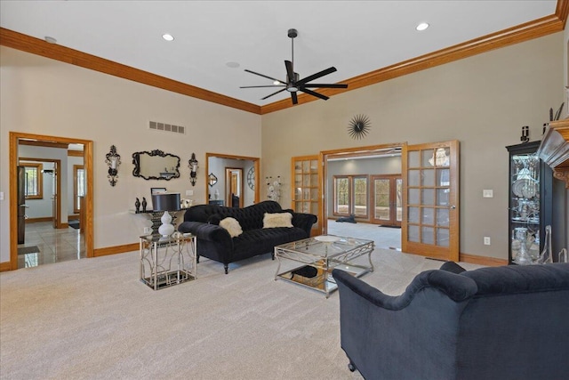 living area with light colored carpet, visible vents, french doors, a ceiling fan, and a high ceiling