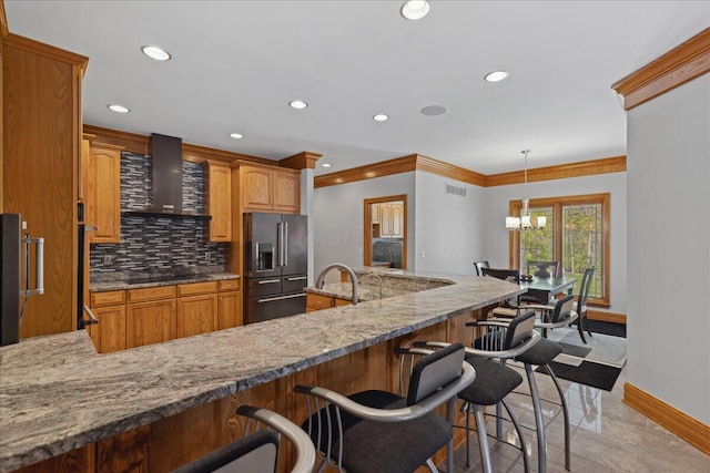 kitchen featuring decorative backsplash, a chandelier, black appliances, baseboards, and wall chimney exhaust hood
