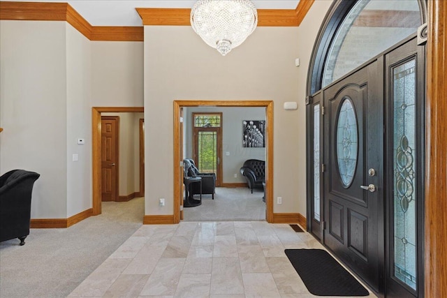 entryway featuring a towering ceiling, a chandelier, light carpet, and baseboards