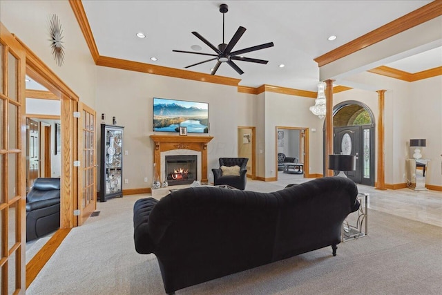 living room featuring ceiling fan, baseboards, a glass covered fireplace, ornamental molding, and light carpet