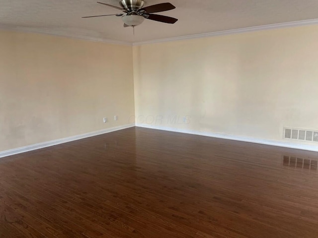 empty room featuring ornamental molding, visible vents, dark wood-type flooring, and a ceiling fan