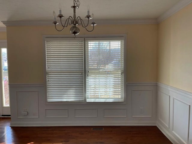 unfurnished dining area with crown molding, a notable chandelier, and a decorative wall