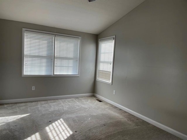 spare room featuring baseboards, vaulted ceiling, and carpet flooring