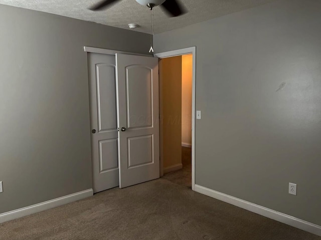 unfurnished bedroom with a textured ceiling, a closet, carpet flooring, and baseboards