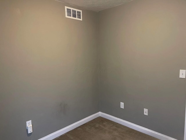 spare room with baseboards, visible vents, dark colored carpet, and a textured ceiling