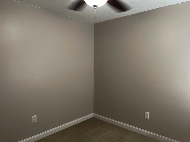 spare room with dark carpet, a ceiling fan, and baseboards