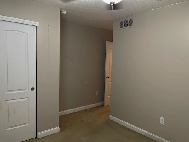 unfurnished room featuring baseboards, a textured ceiling, visible vents, and light colored carpet