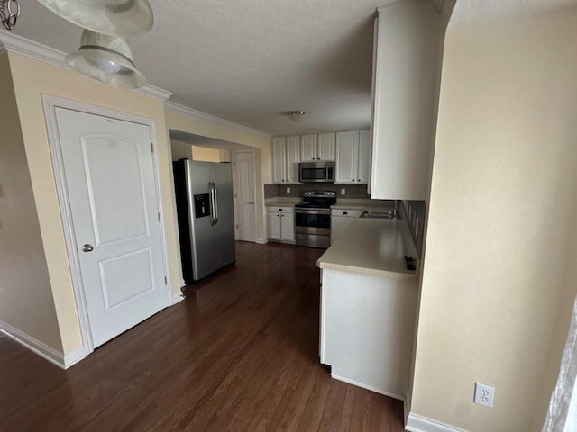 kitchen featuring ornamental molding, stainless steel appliances, dark wood-type flooring, and white cabinets