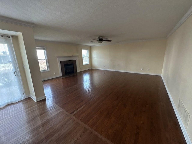 unfurnished living room featuring baseboards, dark wood finished floors, ceiling fan, a fireplace with flush hearth, and ornamental molding