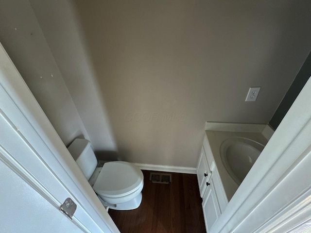 bathroom with toilet, wood finished floors, vanity, visible vents, and baseboards