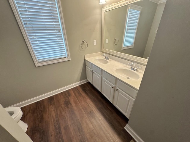 bathroom with toilet, a sink, baseboards, and wood finished floors