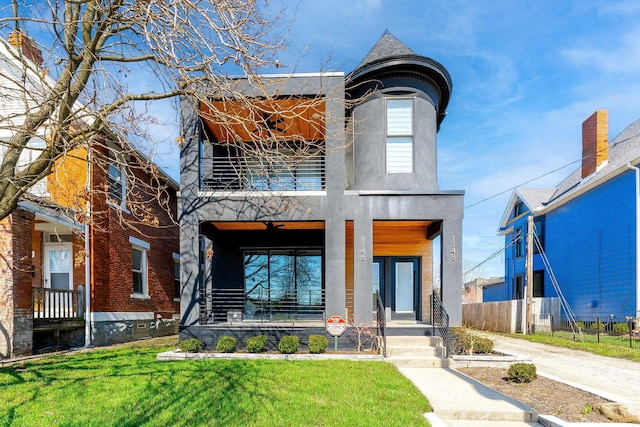 view of front of property with stucco siding, covered porch, fence, a balcony, and a front lawn