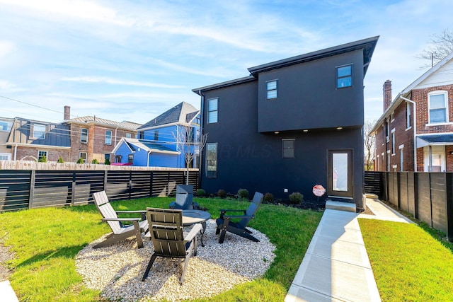 back of property with an outdoor fire pit, a lawn, fence private yard, and stucco siding