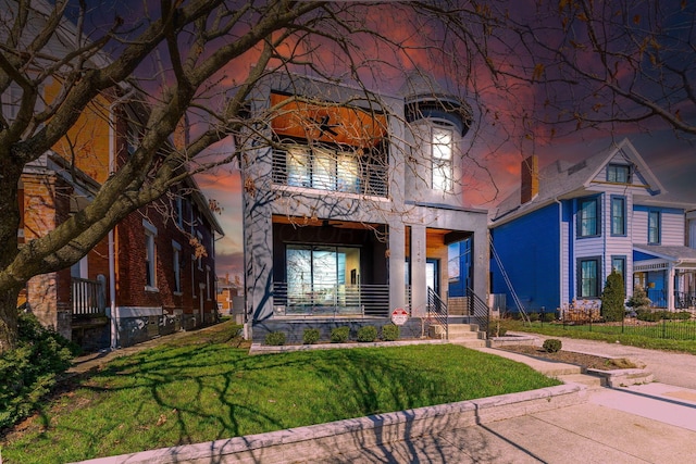 view of front of house featuring covered porch, a front lawn, and a balcony