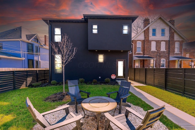 rear view of property with a patio, a fenced backyard, a fire pit, a lawn, and stucco siding