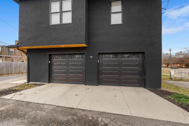 garage featuring driveway and fence