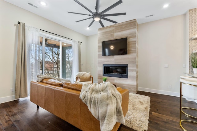 living room with dark wood finished floors, a tile fireplace, visible vents, and baseboards