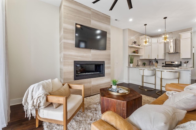 living room with ceiling fan, recessed lighting, a premium fireplace, baseboards, and dark wood finished floors