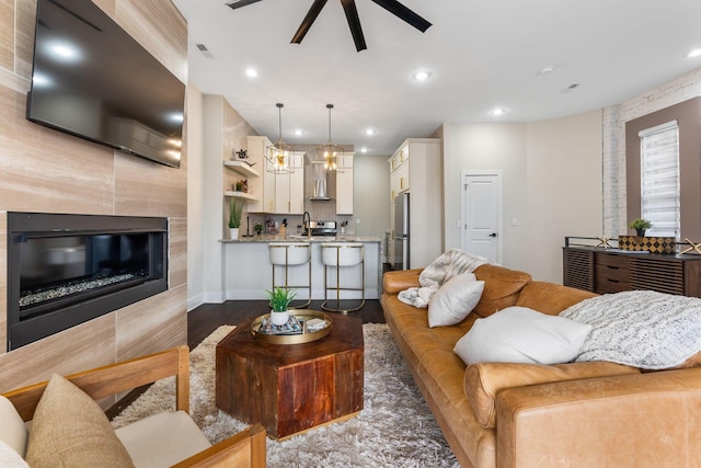 living area featuring a ceiling fan, recessed lighting, dark wood finished floors, and a tile fireplace