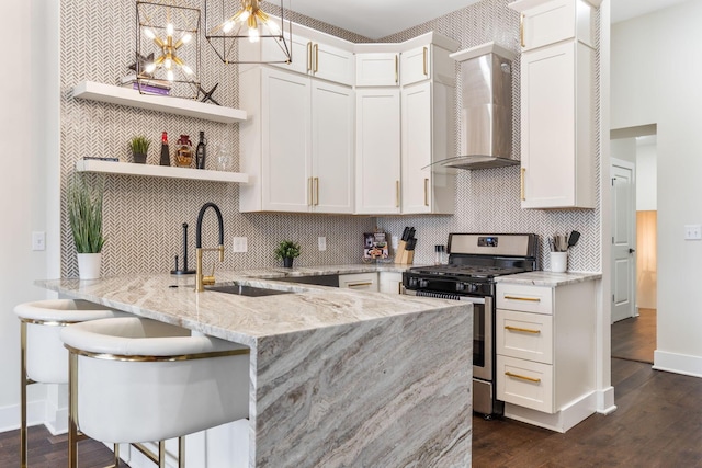 kitchen with stainless steel gas range oven, dark wood-type flooring, wall chimney range hood, open shelves, and a sink