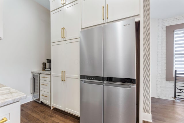 kitchen featuring beverage cooler, white cabinets, freestanding refrigerator, light stone countertops, and dark wood-style floors