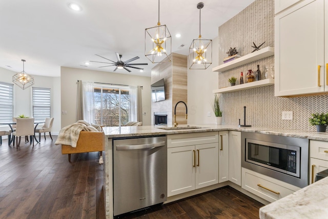 kitchen featuring stainless steel appliances, dark wood-type flooring, a peninsula, a sink, and open floor plan