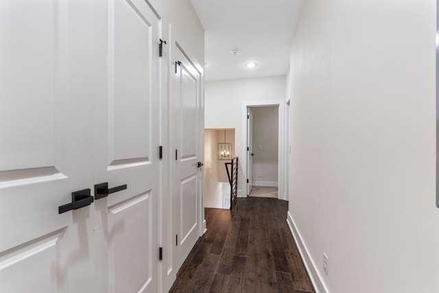 hall featuring dark wood-style floors, an upstairs landing, and baseboards