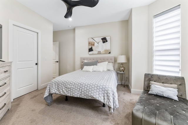 bedroom with light carpet, ceiling fan, baseboards, and multiple windows