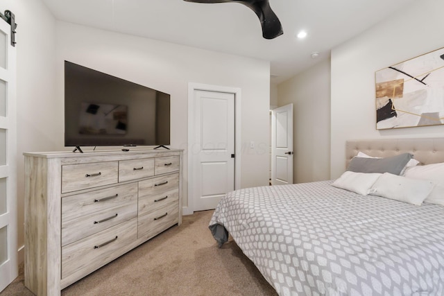 bedroom featuring ceiling fan, a barn door, recessed lighting, and light colored carpet