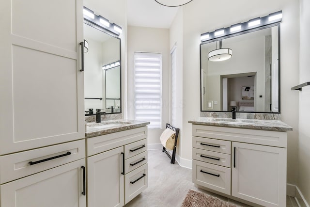 ensuite bathroom featuring ensuite bath, two vanities, and a sink