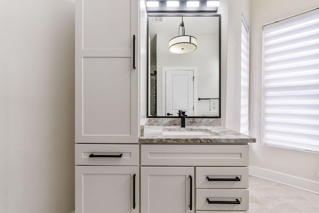 bathroom featuring plenty of natural light, vanity, and baseboards