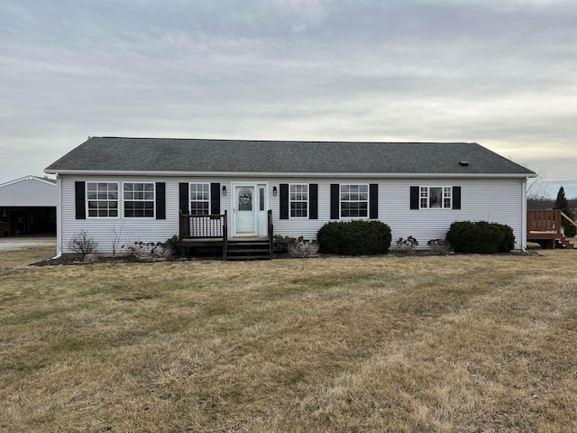 ranch-style home with a front lawn and roof with shingles