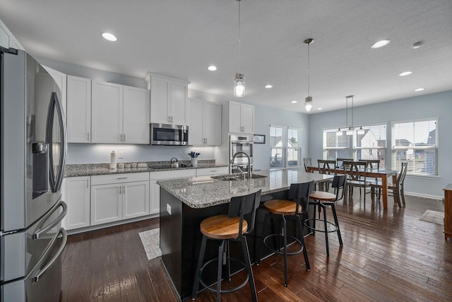 kitchen featuring a sink, stainless steel appliances, light stone counters, and a wealth of natural light