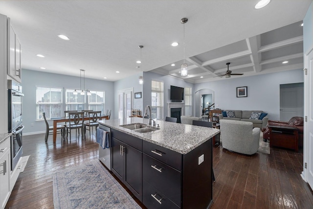 kitchen with dark wood finished floors, a fireplace, coffered ceiling, stainless steel appliances, and a sink