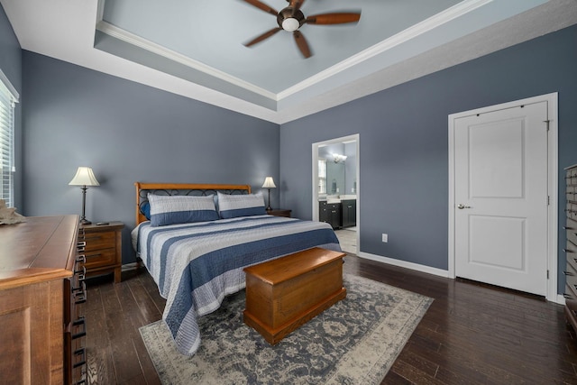 bedroom with a tray ceiling, connected bathroom, wood-type flooring, crown molding, and baseboards