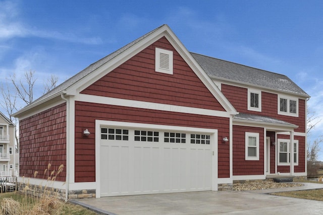 view of front of home with driveway, an attached garage, and roof with shingles